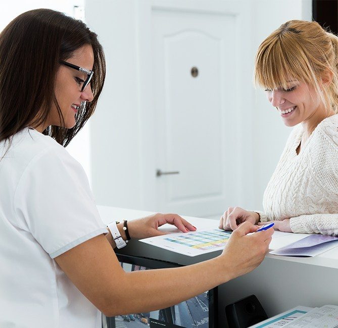 Woman checking in with periodontal team member at front desk