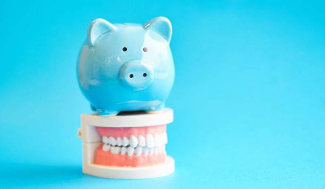 piggy bank and model teeth representing cost of all-on-4 dental implants in San Antonio