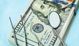 Money and dental tools representing cost of All-On-4 dental implants in San Antonio