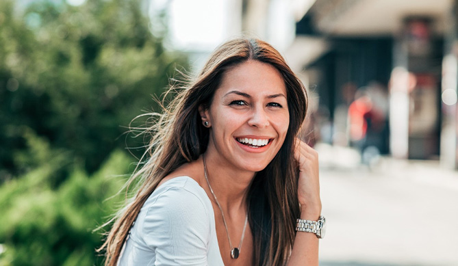 Woman sitting outside smiling with dental implants in San Antonio, TX