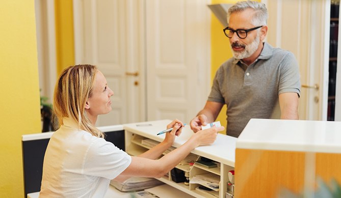 An older man speaking with a dental employee.