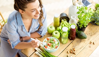 A young woman eating a salad while sitting at a table