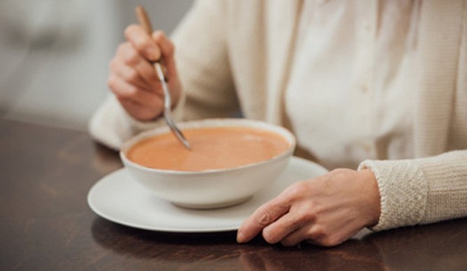 a patient enjoying a bowl of soup following their dental implant placement in San Antonio, TX