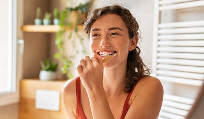 a patient brushing her teeth after receiving dental implants in San Antonio, TX