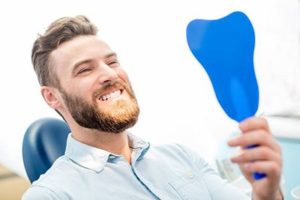 Male patient looking in dental mirror