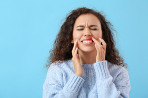 Woman in sweater with inflamed gums due to gingivitis